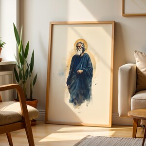 May include: A framed wall art print featuring a watercolor-style illustration of a bearded figure with long hair wearing a dark blue robe. The figure is centered against a light cream background with a soft golden circular halo behind the head.