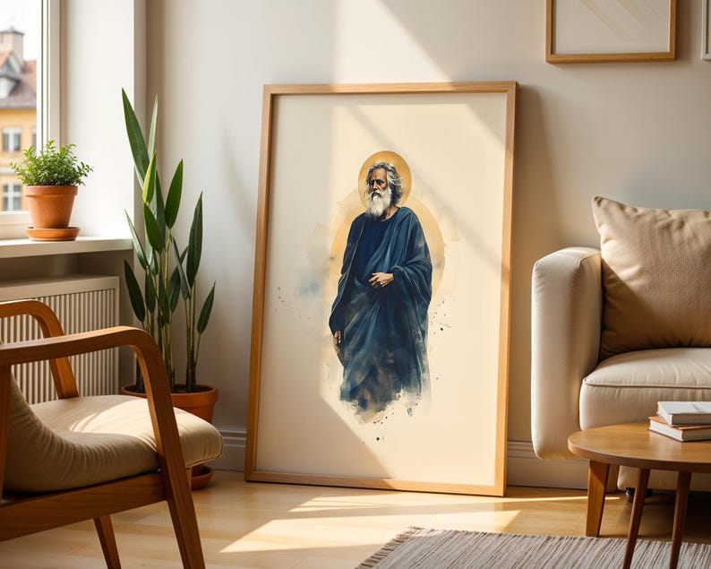 May include: A framed wall art print featuring a watercolor-style illustration of a bearded figure with long hair wearing a dark blue robe. The figure is centered against a light cream background with a soft golden circular halo behind the head.
