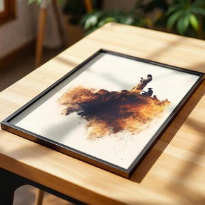 May include: A rectangular framed print featuring an artistic illustration of figures standing on a dark, textured, cloud-like formation. The artwork uses shades of brown, black, and cream, set within a thin black frame on a light wooden surface.