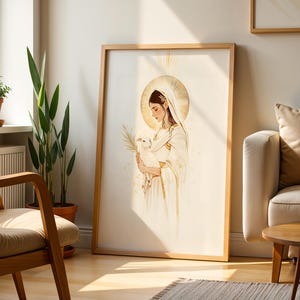May include: A framed vertical wall art print featuring a stylised illustration of a figure in a white robe and veil holding a small white lamb. The figure has a golden halo behind their head and holds a palm frond, rendered in soft gold and cream tones.