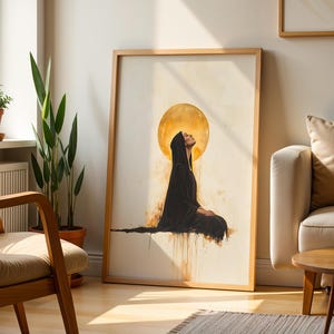 May include: A framed wall art print featuring a figure in a black hooded robe sitting in profile against a large, glowing golden circular background. The artwork uses watercolour-style drips and splatters in shades of gold, brown, and black.