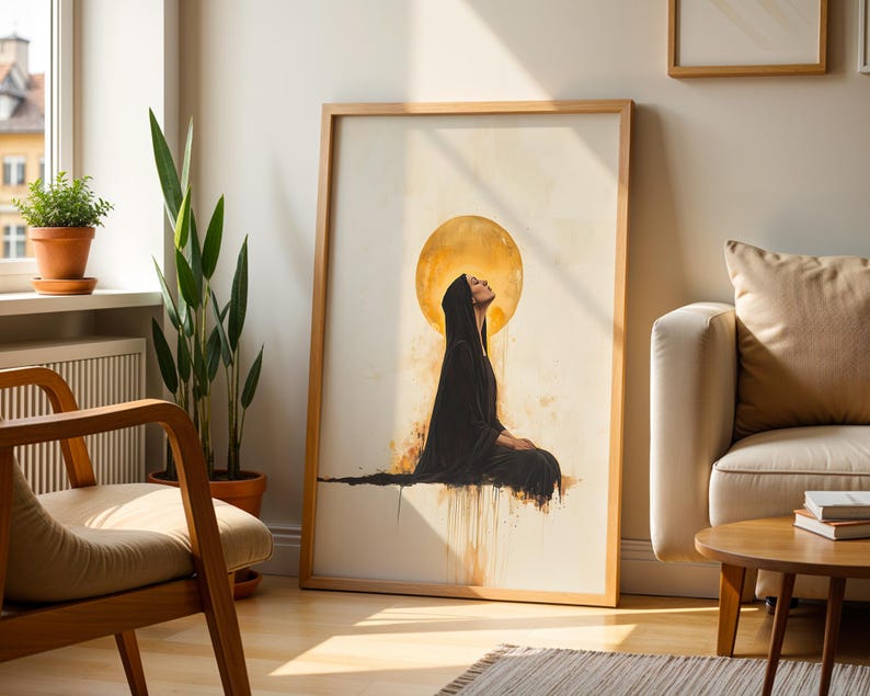 May include: A framed wall art print featuring a figure in a black hooded robe sitting in profile against a large, glowing golden circular background. The artwork uses watercolour-style drips and splatters in shades of gold, brown, and black.