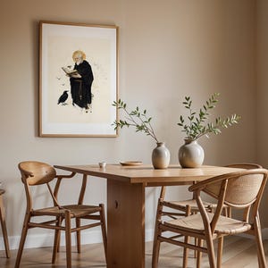 Peut inclure: Une impression encadr&eacute;e repr&eacute;sentant un moine barbu en habit noir lisant un livre avec un corbeau &agrave; proximit&eacute;, expos&eacute;e au-dessus d'une table &agrave; manger en bois clair avec deux chaises, deux vases en c&eacute;ramique avec des branches et un tabouret.