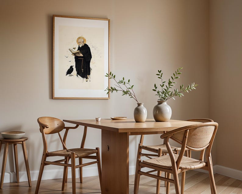 Peut inclure: Une impression encadr&eacute;e repr&eacute;sentant un moine barbu en habit noir lisant un livre avec un corbeau &agrave; proximit&eacute;, expos&eacute;e au-dessus d'une table &agrave; manger en bois clair avec deux chaises, deux vases en c&eacute;ramique avec des branches et un tabouret.