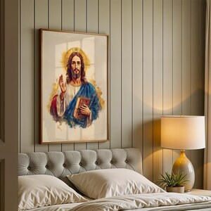 May include: A framed vertical wall art print featuring a watercolor-style illustration of a figure with long brown hair and a beard, wearing a white robe and blue cloak, holding a book, with a golden halo and abstract gold paint splashes.