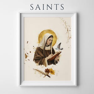 May include: A framed wall art print titled SAINTS featuring a figure in a brown habit and white head covering writing in a book. A golden halo surrounds the head, a small bird flies nearby, and a quill pen rests near yellow and brown flowers.