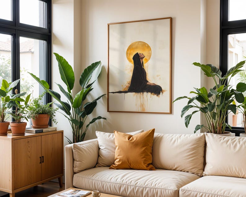 May include: A framed wall art print featuring a figure in a black hooded cloak sitting in profile against a large, glowing golden circular background. The artwork uses a watercolour style with drips of gold and black paint extending downwards.