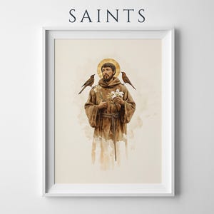 May include: A framed art print featuring the word SAINTS at the top. The illustration depicts a bearded figure in a brown hooded robe with a gold halo, holding white flowers, with a small bird perched on each shoulder, set against a cream background.