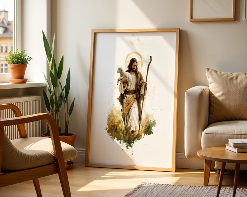 May include: A framed watercolour-style print featuring a figure with long brown hair and a beard, wearing tan robes and holding a small white lamb. The figure carries a wooden staff and has a golden halo behind their head, set against a white background.