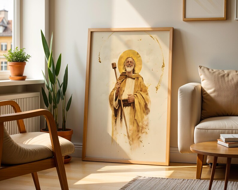 May include: A framed vertical wall art print featuring a watercolor-style illustration of a smiling, bearded figure with a golden halo, wearing tan robes and holding a wooden staff, set against a light cream background with gold accents.