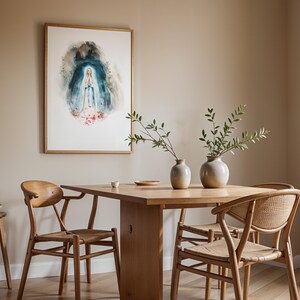 Peut inclure: Une impression aquarelle encadr&eacute;e repr&eacute;sentant une silhouette v&ecirc;tue d'une robe blanche et bleue, les mains jointes en pri&egrave;re, entour&eacute;e d'une aura bleu fonc&eacute; avec des accents floraux rouges &agrave; la base, accroch&eacute;e au-dessus d'une table en bois.