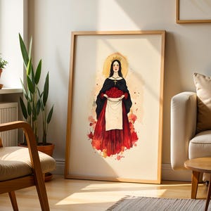 Pu&ograve; includere: Una stampa artistica da parete incorniciata con un'illustrazione ad acquerello di una figura con corona, mantello nero e gonna rossa, che regge un grembiule bianco pieno di rose rosse. La figura indossa una collana a croce e un'aureola.