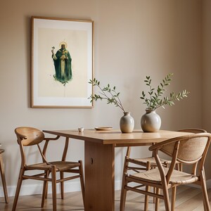 May include: A framed wall art print featuring a figure in a dark green robe and crown holding a shamrock, displayed above a wooden dining table with two ceramic vases containing green branches and two wooden chairs with woven seats.