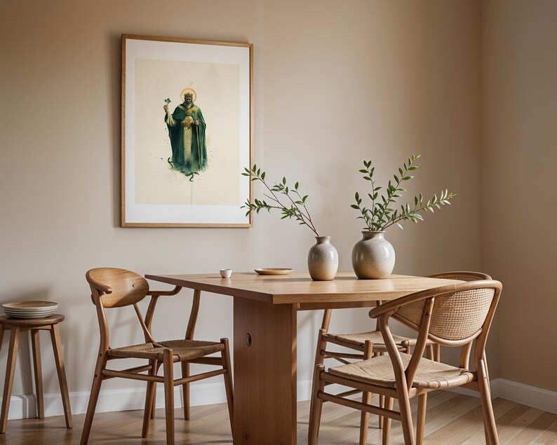 May include: A framed wall art print featuring a figure in a dark green robe and crown holding a shamrock, displayed above a wooden dining table with two ceramic vases containing green branches and two wooden chairs with woven seats.