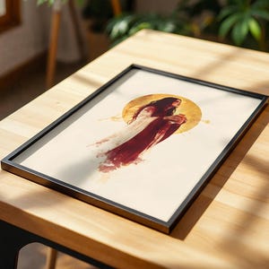 Puede incluir: Una l&aacute;mina de arte enmarcada que presenta la ilustraci&oacute;n central de una persona con cabello largo y oscuro que viste una prenda fluida de color blanco y rojo intenso. La figura se sit&uacute;a sobre un gran elemento circular amarillo dorado.