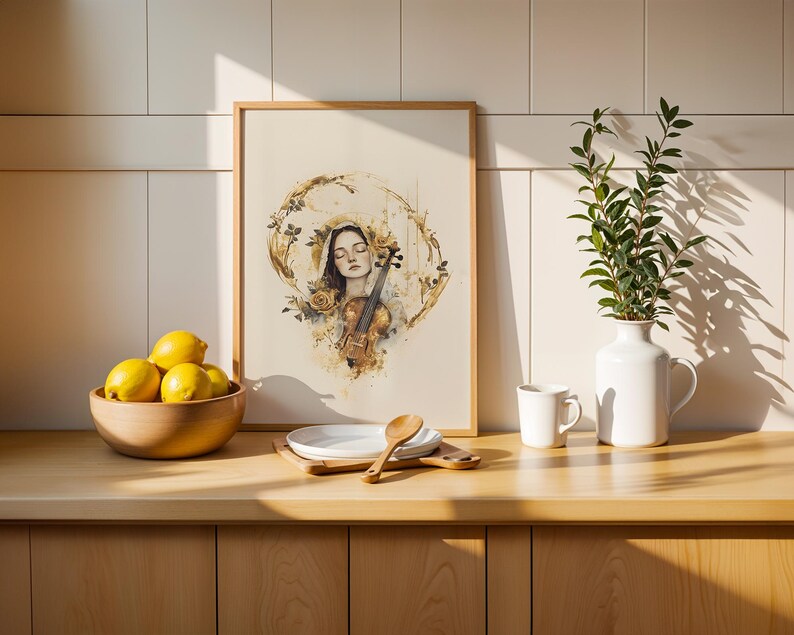 Op de afbeelding: Een ingelijste kunstdruk met een aquarelillustratie van een persoon met gesloten ogen die een viool vasthoudt, omringd door gouden bloemaccenten. De print staat op een houten aanrecht naast een schaal met gele citroenen en een witte vaas.