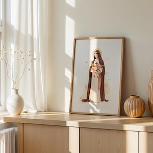 Peut inclure: Une impression d'art encadr&eacute;e repr&eacute;sentant une illustration &agrave; l'aquarelle d'un personnage en habit marron et robe blanche tenant un bouquet de fleurs et une croix, avec un halo dor&eacute; derri&egrave;re la t&ecirc;te, sur un fond clair et doux.
