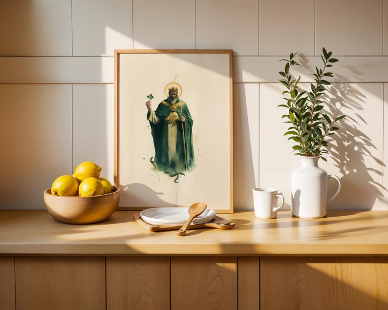 May include: A framed vertical art print featuring a bearded figure in a dark green robe and crown, holding a shamrock and a staff. The print is displayed on a wooden counter next to a wooden bowl of yellow lemons, a white plate, a spoon, and a white vase.