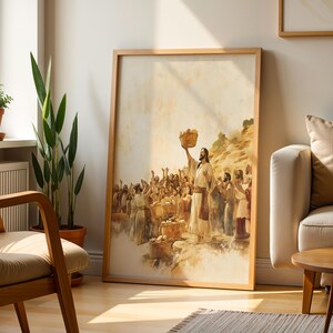 May include: A framed wall art print featuring a watercolour-style illustration of a figure in robes holding a basket above a crowd of people. The scene depicts a gathering with multiple baskets of bread in warm, muted tones of beige, brown, and gold.