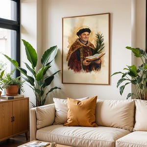 May include: A framed wall art print featuring a watercolour-style portrait of a historical figure wearing a dark cap and a fur-trimmed robe, holding an open book and a green palm frond, with a golden halo depicted behind the head.