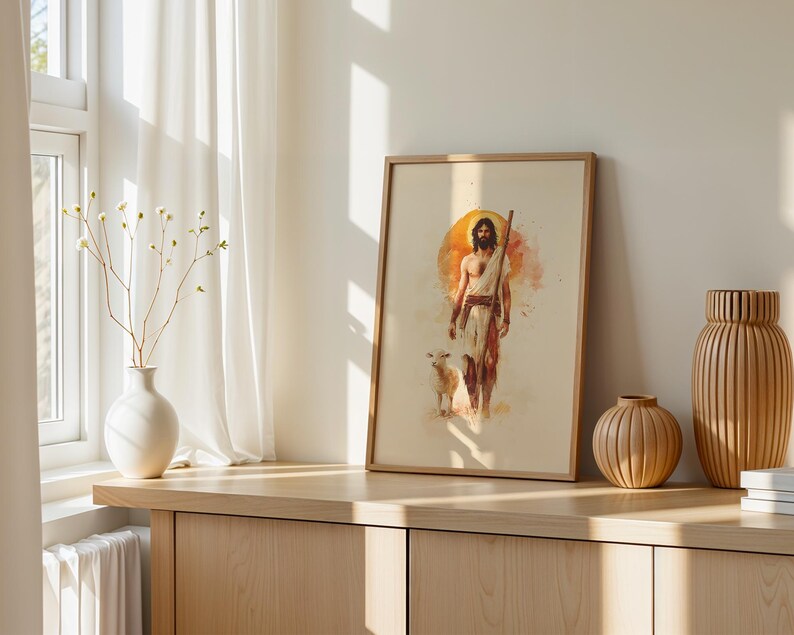Peut inclure: Une impression encadr&eacute;e de style aquarelle repr&eacute;sentant une silhouette barbue v&ecirc;tue de tissus drap&eacute;s tenant un b&acirc;ton, accompagn&eacute;e d'un petit agneau. L'&oelig;uvre pr&eacute;sente un fond circulaire orange chaud et est dans un cadre en bois clair.