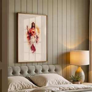 May include: A framed wall art print featuring a watercolor-style illustration of Jesus Christ with a glowing Sacred Heart. The figure is depicted in white and red robes with a crown of thorns, set against a soft, abstract background of warm light.