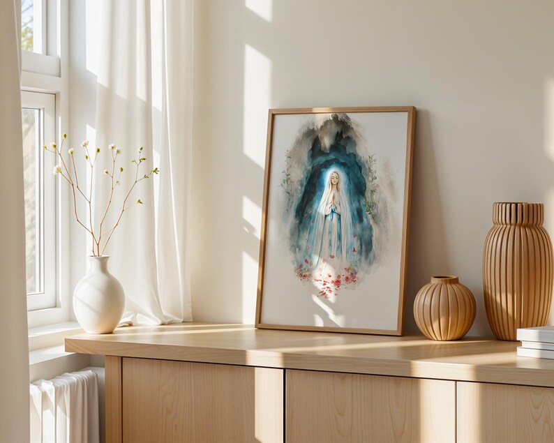 Peut inclure: Une impression aquarelle encadr&eacute;e repr&eacute;sentant une silhouette v&ecirc;tue d'une robe blanche et bleue, les mains jointes en pri&egrave;re, entour&eacute;e d'un fond abstrait bleu fonc&eacute; et gris avec des accents floraux rouges &agrave; la base, dans un cadre en bois clair.
