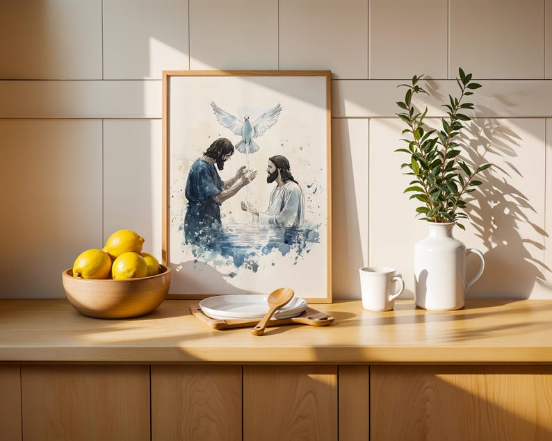Peut inclure: Une impression encadr&eacute;e de style aquarelle repr&eacute;sentant une sc&egrave;ne de bapt&ecirc;me avec deux personnages dans l'eau et une colombe blanche au-dessus, pr&eacute;sent&eacute;e dans une cuisine avec un bol de citrons jaunes, une cuill&egrave;re en bois et un vase blanc.
