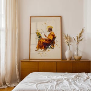 Puede incluir: Una impresi&oacute;n de arte de pared enmarcada que presenta una ilustraci&oacute;n estilo acuarela de una figura barbuda con t&uacute;nicas naranjas sentada en una silla, pintando un retrato de una figura con halo. La obra incluye salpicaduras de pintura dorada.