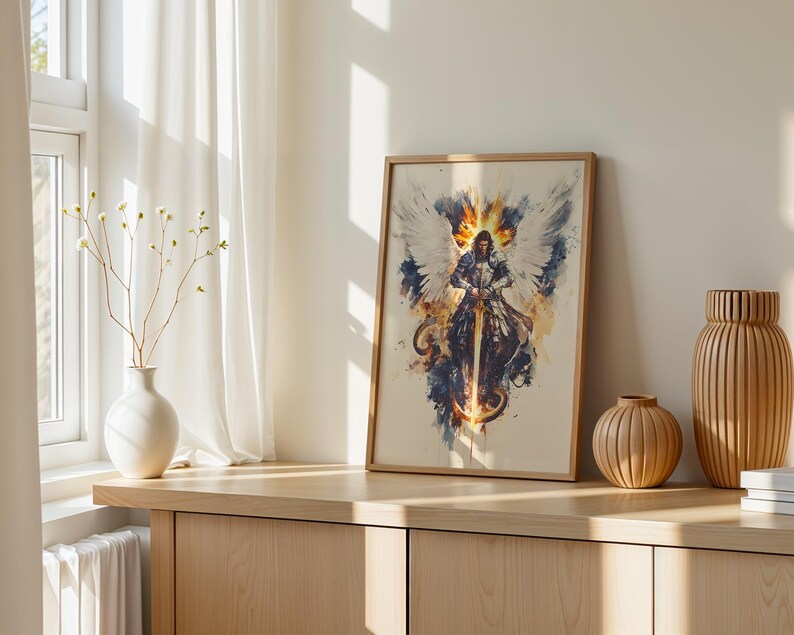 May include: A framed vertical art print featuring a watercolour-style illustration of a winged warrior in armour holding a sword. The artwork displays a central figure with large white wings, surrounded by splashes of orange, yellow, and dark blue ink.