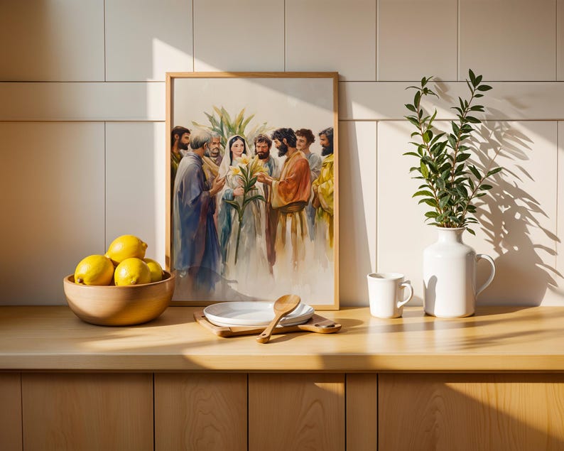 May include: A framed watercolor print depicting a group of figures in robes, with one central figure holding yellow lilies. The artwork is displayed on a wooden counter next to a wooden bowl of lemons, white plates, a wooden spoon, and a white vase.