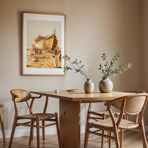 May include: A wooden dining table with four chairs featuring woven seats and curved backrests. Two ceramic vases with green branches sit on the table. A framed print depicting a large wooden ship under construction hangs on the beige wall.