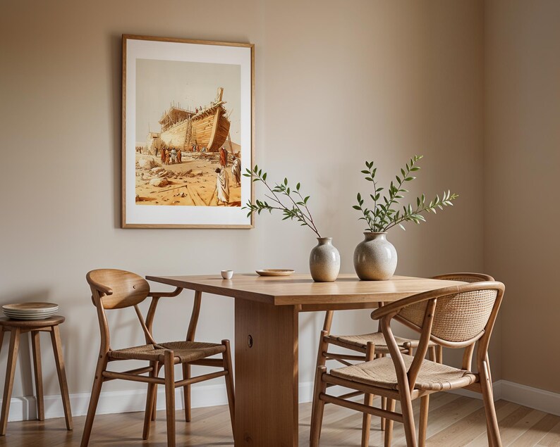 May include: A wooden dining table with four chairs featuring woven seats and curved backrests. Two ceramic vases with green branches sit on the table. A framed print depicting a large wooden ship under construction hangs on the beige wall.