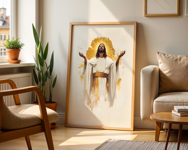 May include: A framed wall art print featuring a watercolour-style illustration of a figure with long hair and a beard, wearing a white robe with a gold sash, arms raised upwards, surrounded by a radiant golden halo against a white background.