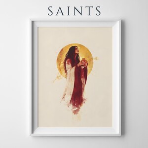 Puede incluir: Una l&aacute;mina enmarcada titulada SAINTS que presenta una ilustraci&oacute;n estilo acuarela de una figura con una t&uacute;nica larga de color rojo oscuro y blanco que sostiene un frasco peque&ntilde;o. La figura se encuentra ante un gran halo dorado circular.