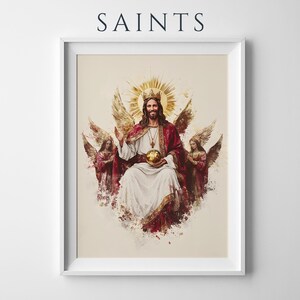 May include: A framed wall art print titled SAINTS featuring a central figure with a golden crown and halo, wearing a red and white robe, holding a golden orb, flanked by two winged angels in red garments, all set against a light cream background.