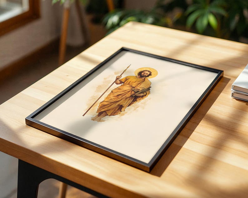Op de afbeelding: Een ingelijste print met een aquarel-stijl illustratie van een bebaard figuur in gouden gewaden die een lange staf en een boek vasthoudt. Het figuur heeft een cirkelvormige gouden halo achter het hoofd op een lichtcr&egrave;me achtergrond in een zwarte lijst.