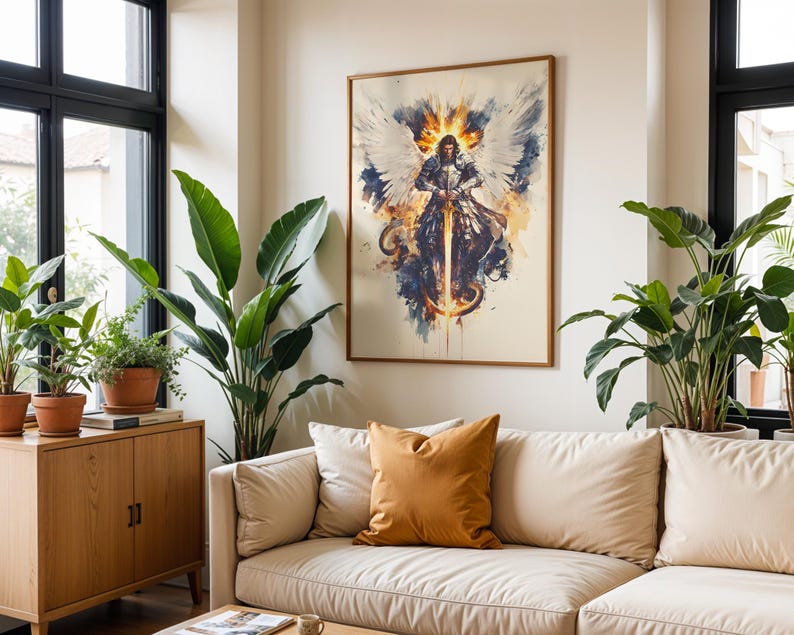 May include: A framed wall art print featuring a central figure in silver armour with large white wings, holding a glowing sword. The artwork uses a watercolour style with splashes of blue, orange, and yellow against a light cream background.