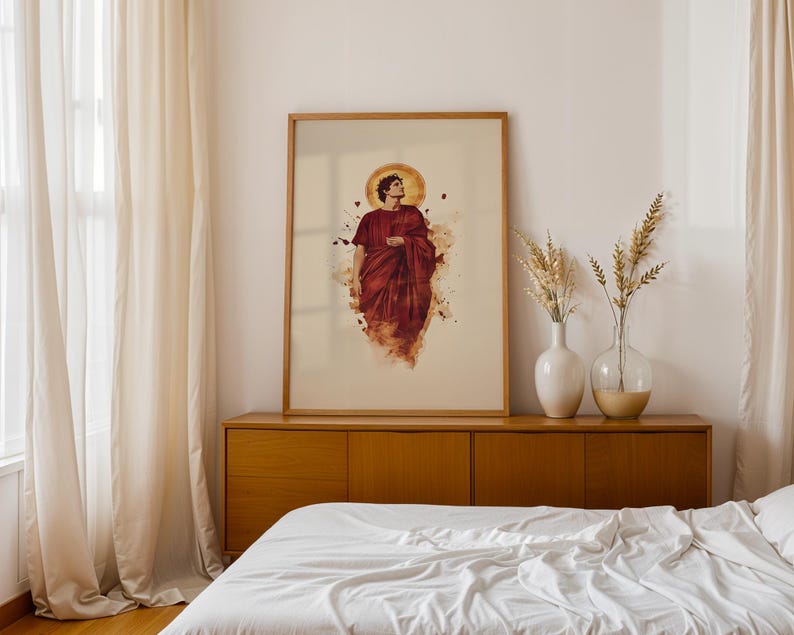 May include: A framed vertical wall art print featuring a figure in a deep red robe with a golden halo, rendered in a watercolour style. The artwork is displayed in a light wood frame, positioned on a wooden sideboard next to two glass vases.