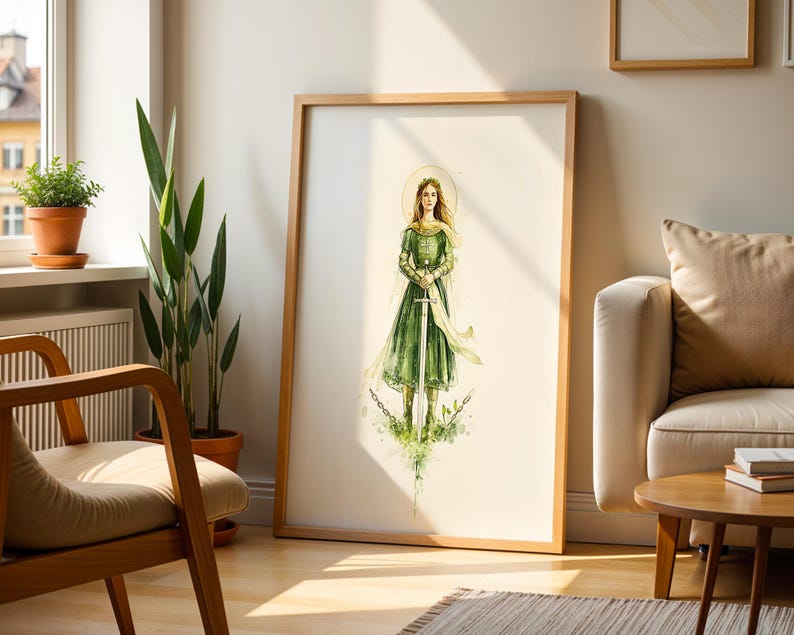 Op de afbeelding: Een ingelijste verticale kunstdruk met een aquarelillustratie van een figuur in een lange groene jurk die een hoog zwaard vasthoudt. De figuur heeft een gouden halo achter het hoofd en staat te midden van gebroken kettingen en groen blad.
