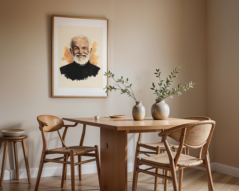 May include: A framed portrait print of a smiling older person with a white beard, wearing a black shirt, displayed on a wall above a wooden dining table with three chairs and two ceramic vases containing green leafy branches.