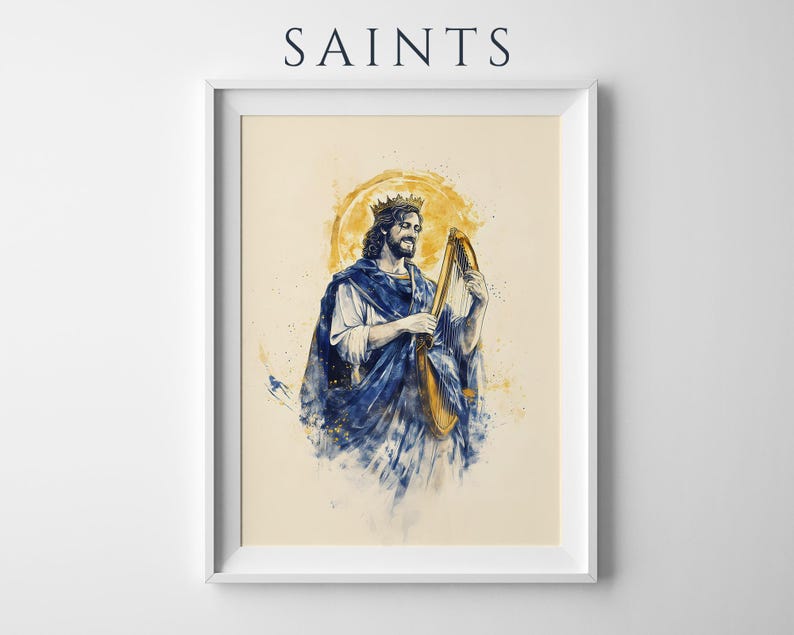 May include: A framed art print titled SAINTS featuring a watercolour-style illustration of a crowned figure with long hair playing a golden harp. The figure wears a flowing blue robe over a white garment, set against a circular yellow halo background.