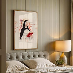 K&ouml;nnte beinhalten: Ein gerahmter Wandkunstdruck, der eine Nonne in einem schwarz-wei&szlig;en Habit mit einem roten Buch zeigt. Die Figur ist vor einem wei&szlig;en Hintergrund zentriert, mit einem sanften, leuchtenden Heiligenschein und abstrakten roten Aquarellspritzern.