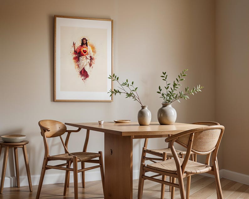 Puede incluir: Una l&aacute;mina de arte enmarcada con una ilustraci&oacute;n estilo acuarela de una figura con un coraz&oacute;n rojo brillante, expuesta sobre una mesa de comedor de madera con dos jarrones de cer&aacute;mica, tres sillas de madera y un taburete peque&ntilde;o con platos.