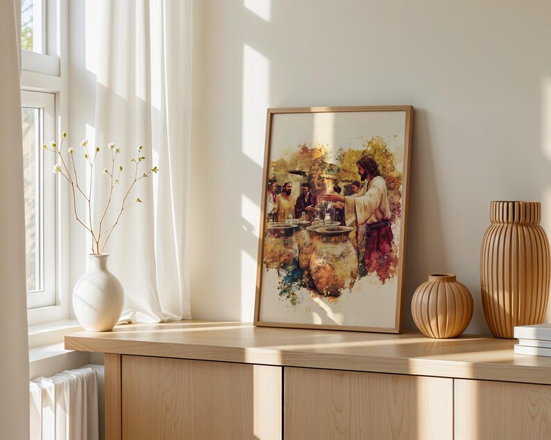 May include: A framed watercolor-style print depicting a biblical scene with a central figure in robes gesturing toward large clay vessels, surrounded by other individuals. The artwork features warm earth tones, splashes of color, and a light-colored frame.