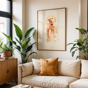 May include: A framed wall art print featuring a watercolor-style illustration of a figure wearing a crown of thorns and a veil, holding a single red rose. The artwork is displayed in a thin wooden frame on a plain wall above a beige sofa.