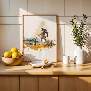 May include: A framed watercolor print depicting a small figure reaching toward a giant, displayed on a wooden counter next to a bowl of yellow lemons, a white plate with a wooden spoon, a white mug, and a white vase containing green leafy branches.