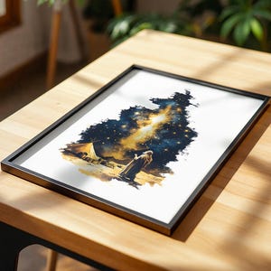 May include: A framed print featuring a watercolour-style illustration of a person standing in a desert landscape at night, looking up at a bright, glowing nebula in the starry sky, with a small tent visible nearby on the sandy ground.