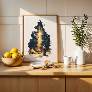 May include: A framed rectangular wall art print featuring a dark blue and gold celestial night sky scene with a figure standing near a tent in a desert landscape. The artwork is displayed on a wooden counter next to a bowl of yellow lemons.