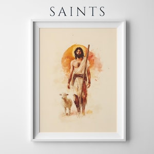 May include: A framed art print titled SAINTS featuring a watercolor illustration of a bearded figure in a white robe holding a wooden staff, accompanied by a small lamb. The background displays a warm orange circular sun motif on a cream field.